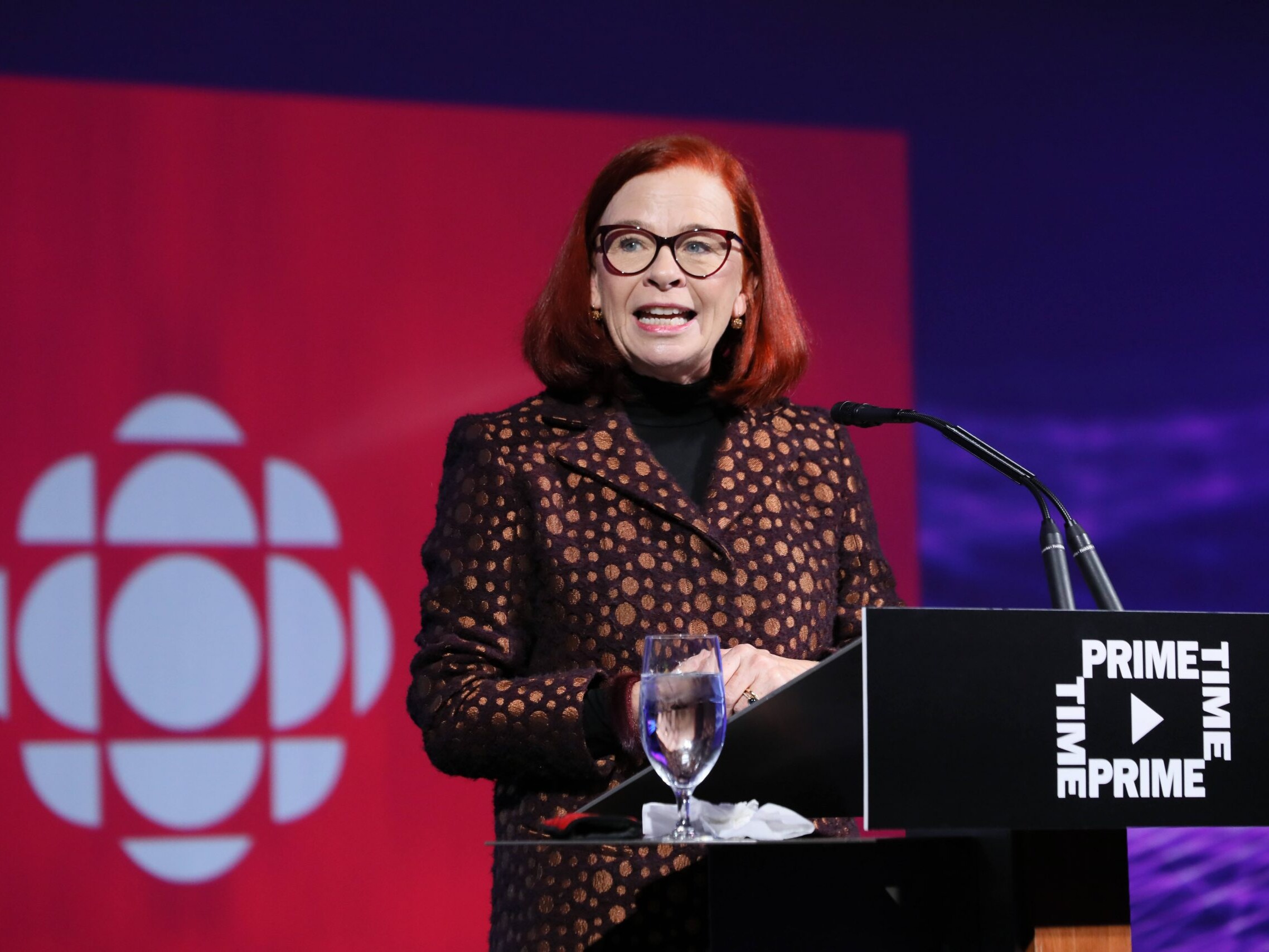Catherine Tait speaking at a podium in front of the CBC gem logo.