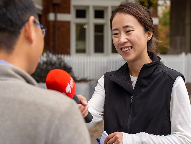 A reporter holding an SBS-branded microphone interviews someone.