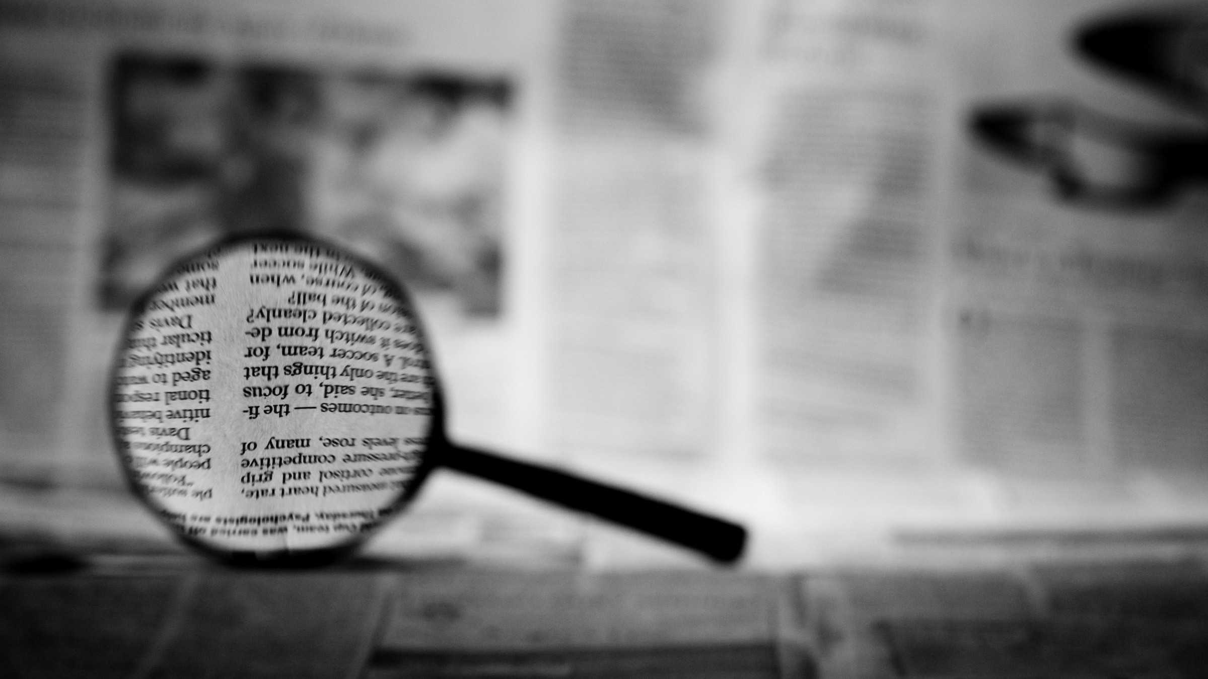 Image of a magnifying glass over a newspaper.