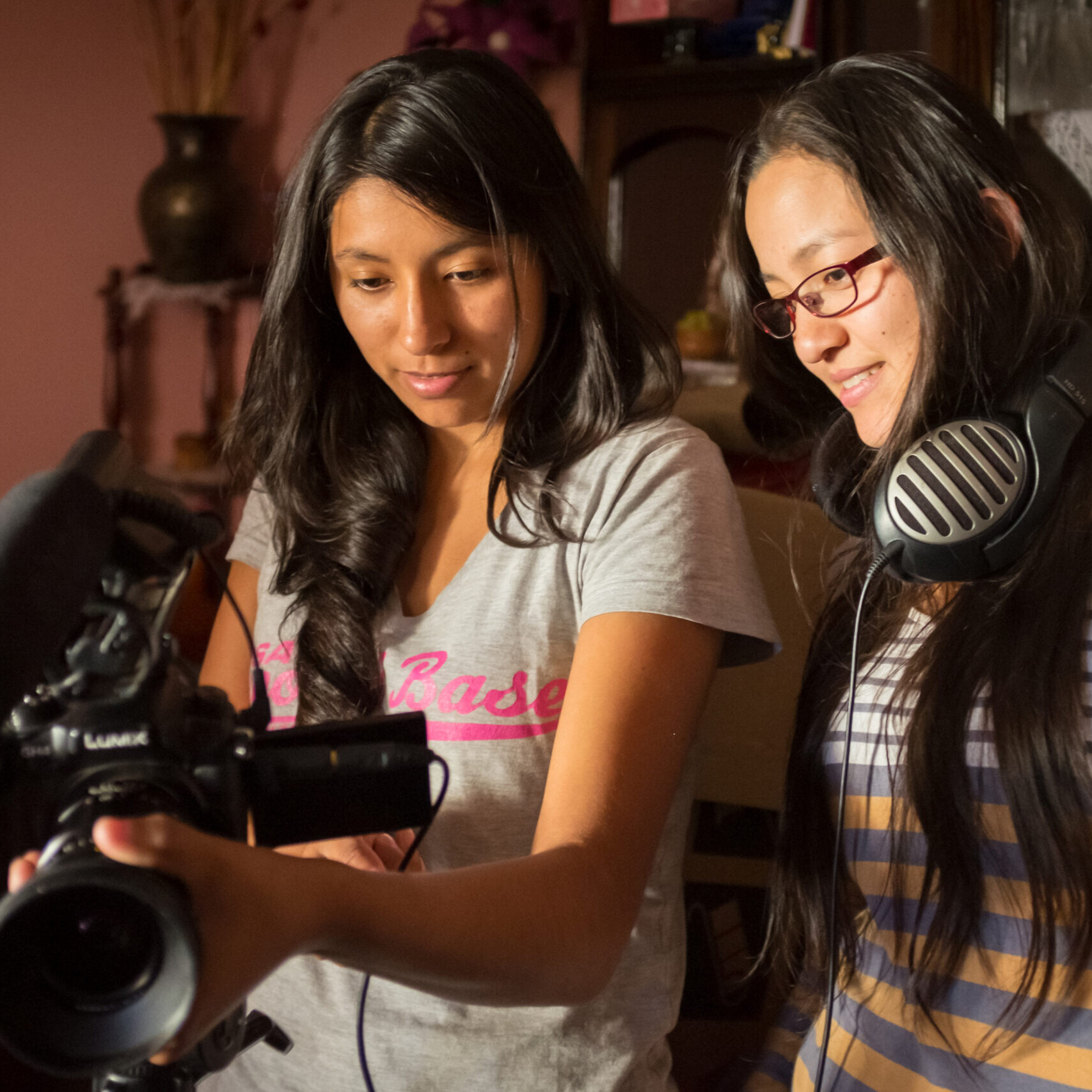 Two women standing examining a camera
