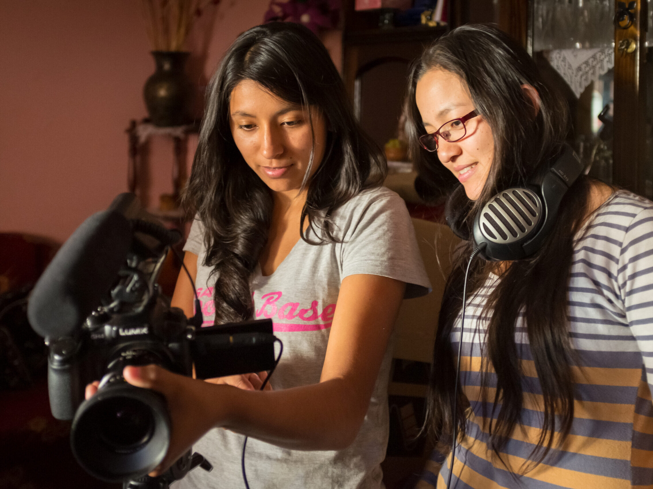 Two women standing examining a camera