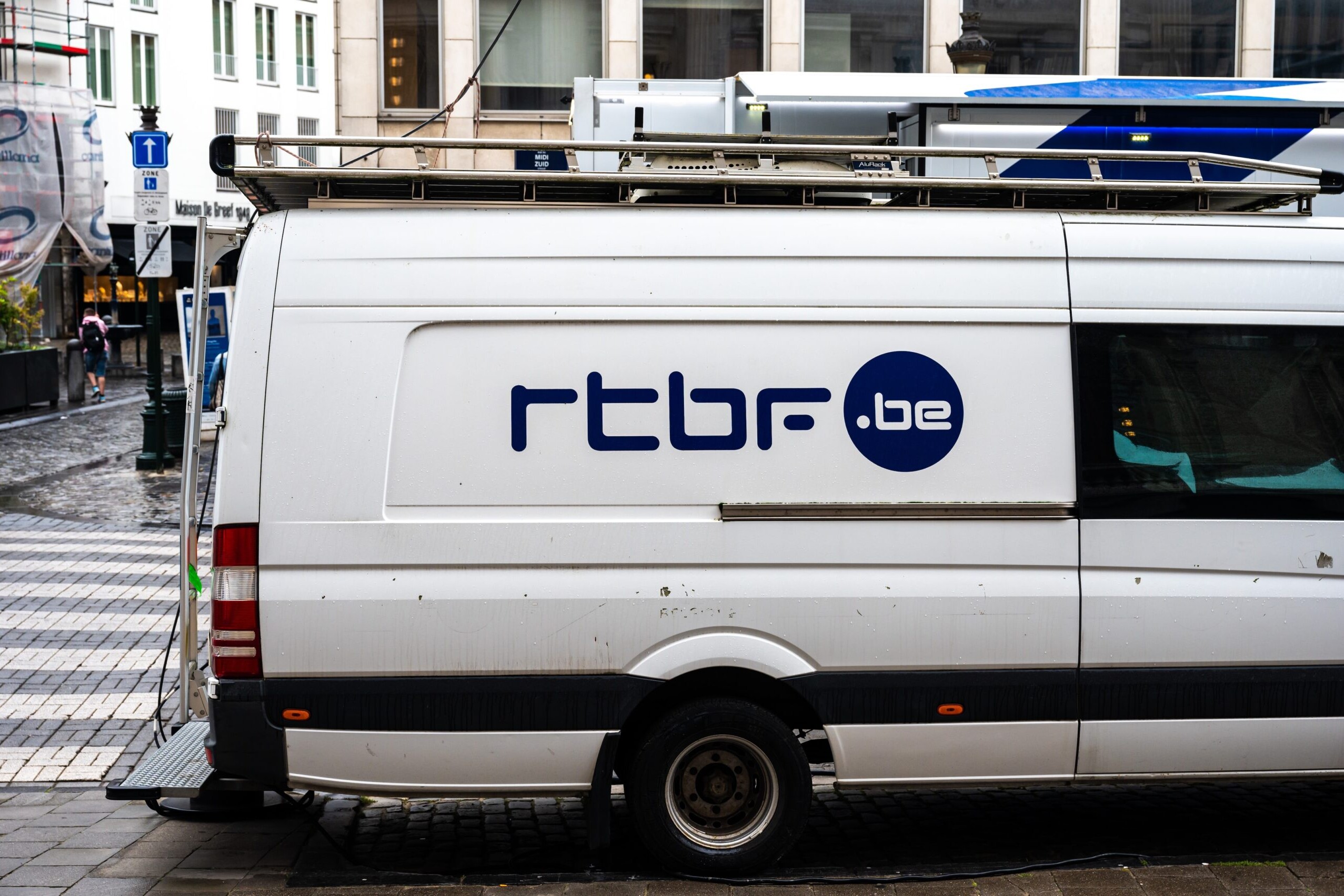 A white van parked on the side of a road with rtbf branding.