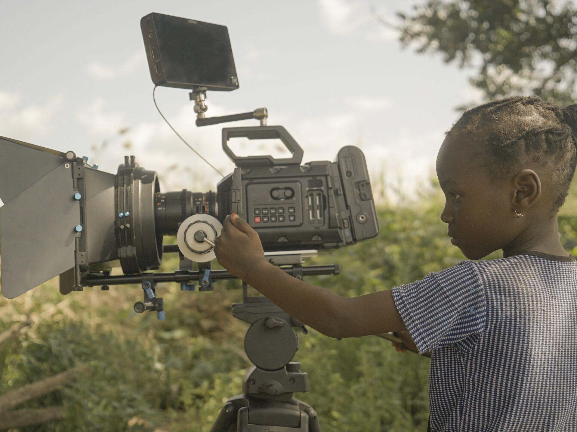 A young girl in profile is operating a camera.
