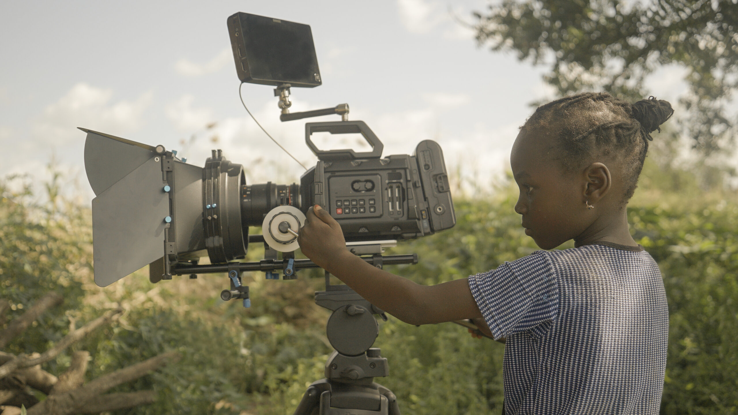 A young girl in profile is operating a camera.
