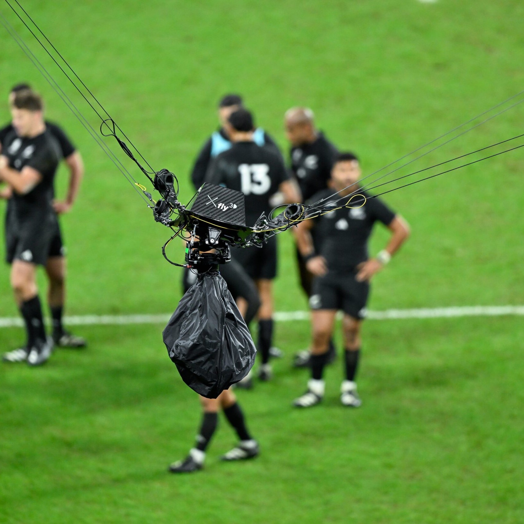 A spider cam in focus, against a blurred background of a rugby pitch.