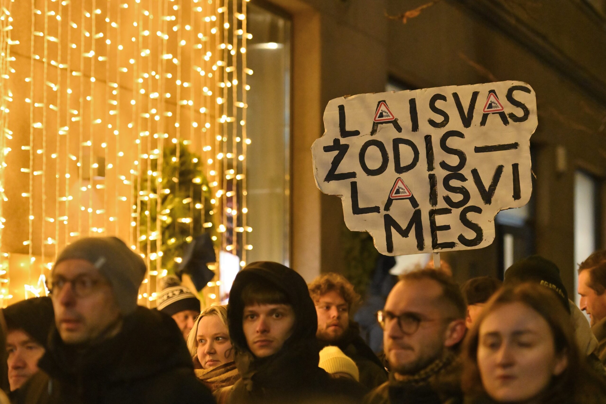 group of people walking in the street with sign